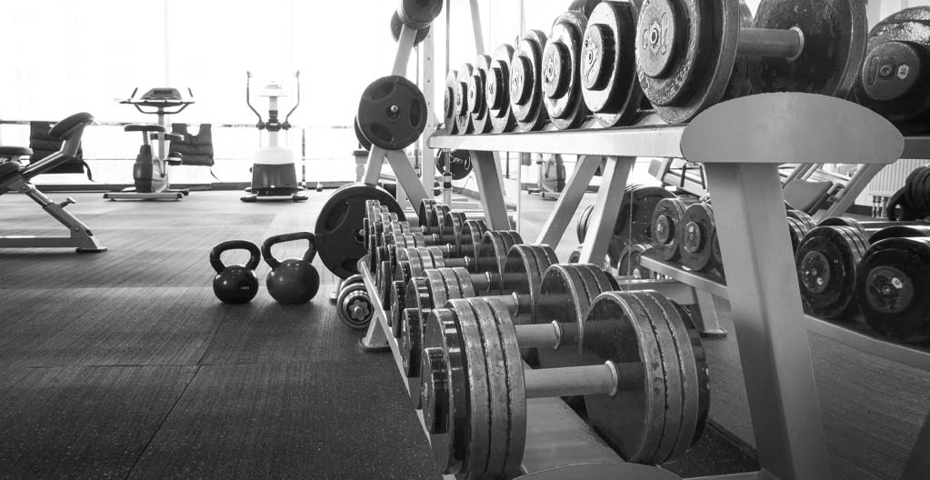 Dumbbells and other exercise equipment like treadmills in a gym.