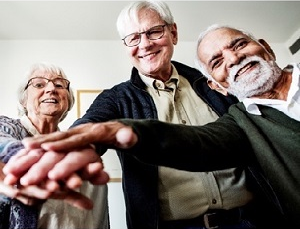 Three older adults put their hands together.