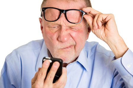 Man squints closely at a cell phone.