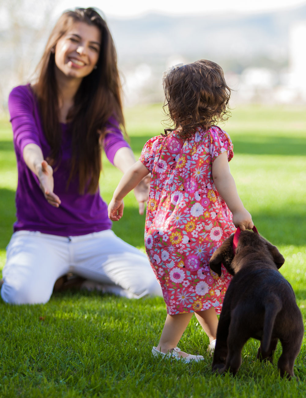 woman holding arms out towards toddler and puppy