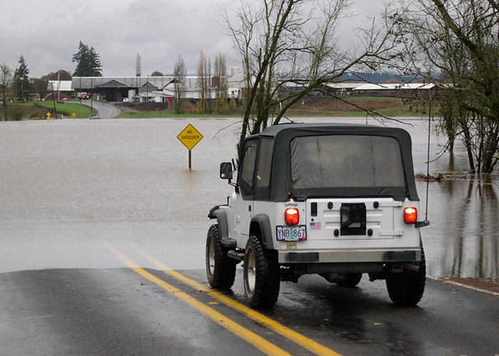 A car comes to a stop at the waterline of a flooded road