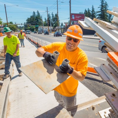 An ODOT worker holds up construction materials as he unloads them from a truck.