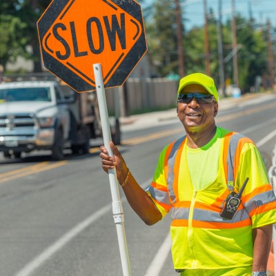 A male ODOT worker stands on a toradway holding a 