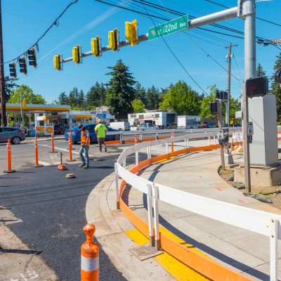 A roadway intersection under construction with orange traffic cones and barriers.