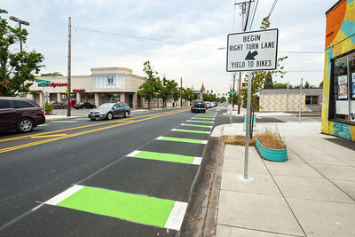 Local road with a green and white striped bike lane. Sign reads "Begin right turn lane.  Yield to bikes"