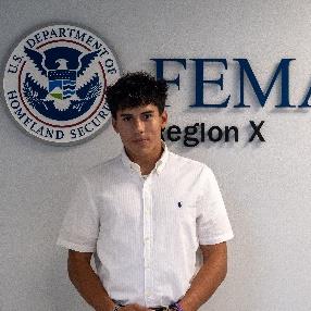 Person standing in front of a wall with a FEMA Region 10 logo