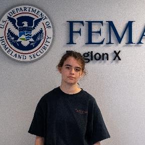 Person standing in front of a wall with a FEMA Region 10 logo