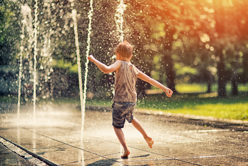 Image of a boy splashing in a fountain