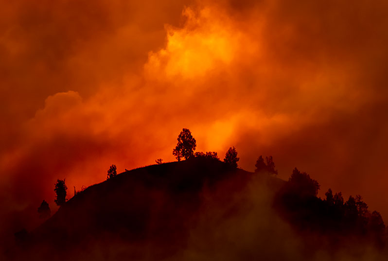 Image of smoke and fire filled mountain top with orange smoky skies